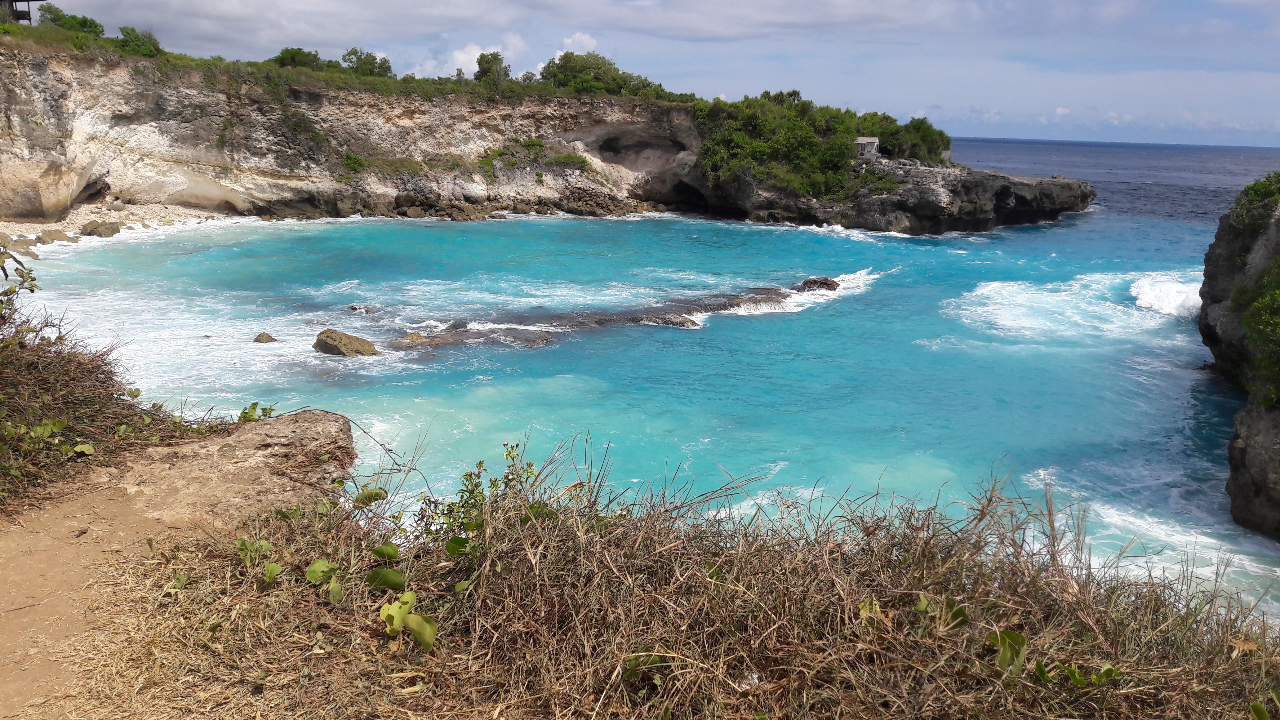 Blue Lagoon on Nusa Ceningan, turquoise inlet below limestone cliffs, seen from the clifftop path