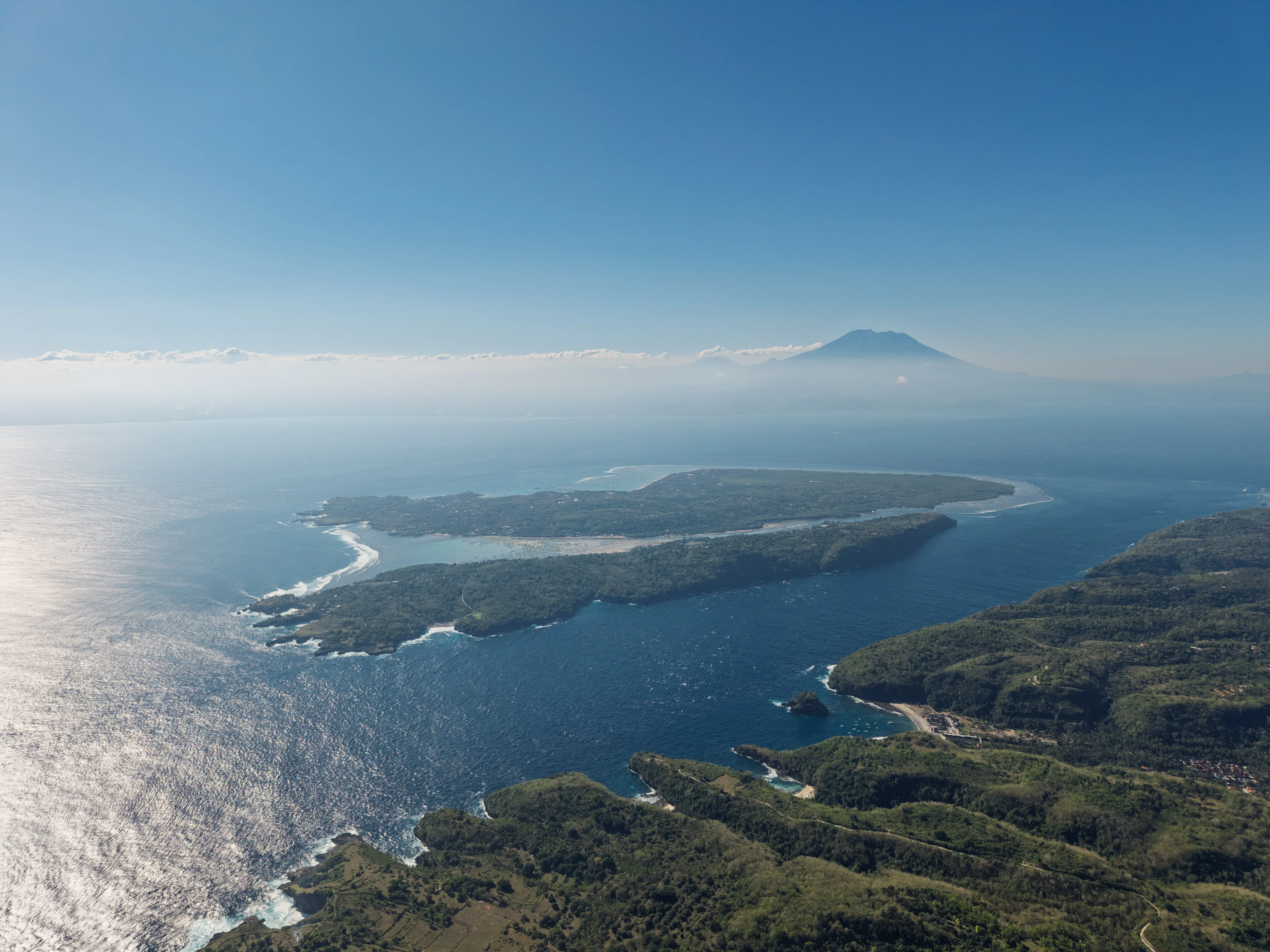 Aerial view from Nusa Penida over Nusa Ceningan and Nusa Lembongan, with Mount Agung on Bali in the distance